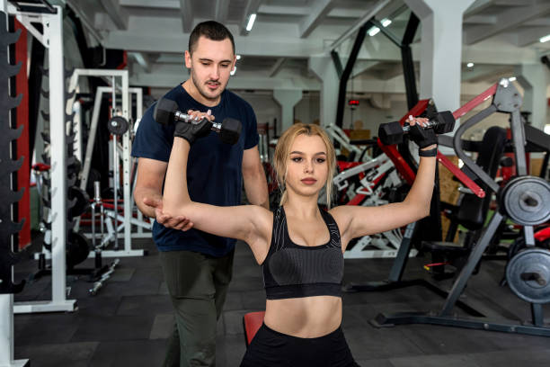 istock Personal male instructor helping woman doing exercise with heavy dumbbells 1397041045