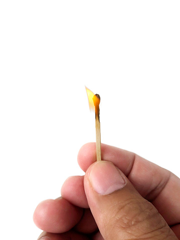 Hand holding burning match stick. Photo on a white background