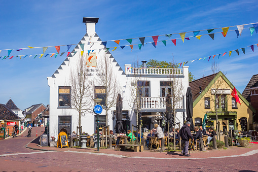 Little white cafe with people enjoying the sun on the market square of Winsum, Netherlands
