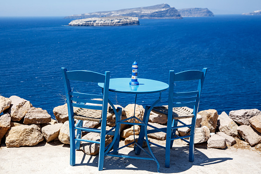 Wooden blue table and chair on the shore of the blue sea. Seaside cafe in Greece
