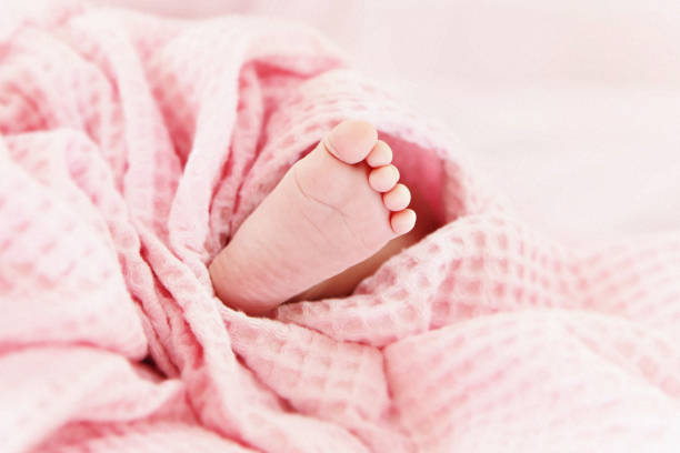 Cute baby foot under pink blanket stock photo