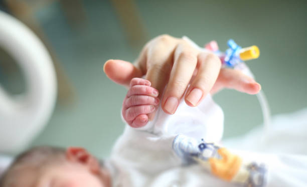 Newborn holding his mother's finger stock photo
