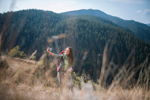 Young Woman Using Smartphone To Take A Selfie In Beutiful Nature