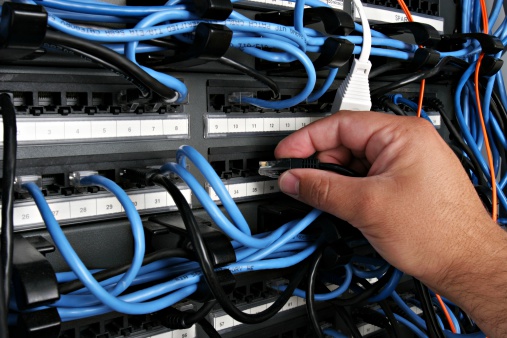 Plugging a black RJ45 into a rack mounted patch panel.