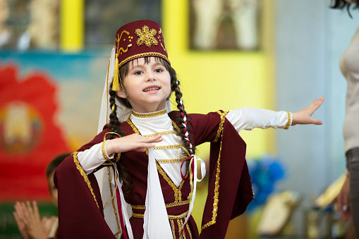 A girl in a national Georgian costume is dancing.