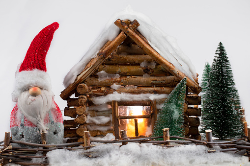 A fabulous Christmas gnome stands next to a miniature wooden house.