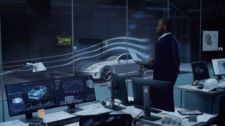 Engineering Research Agency Perform Aerodynamic Testing with a Modern Eco-Friendly Electric Sports Car in a Wind Tunnel. Black Chief Development Officer Works on a Laptop and Changes Testing Options.