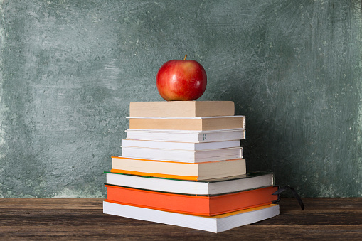 Stack of books and stationery on the background of the school board.