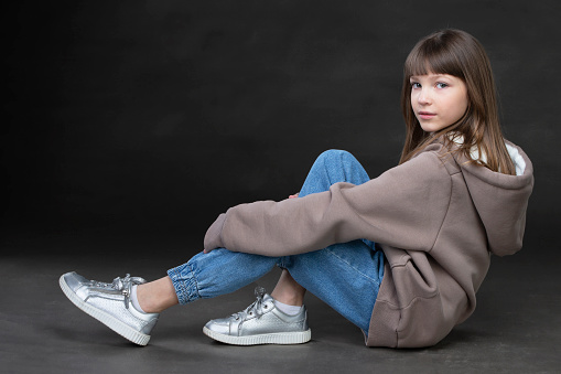 Girl in a sweatshirt and jeans on a gray background. beautiful teen girl.
