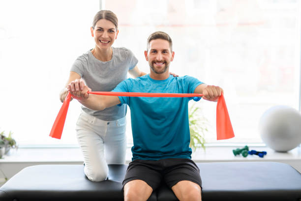 istock Modern rehabilitation physiotherapy woman worker with man client using red elastic 1397054282