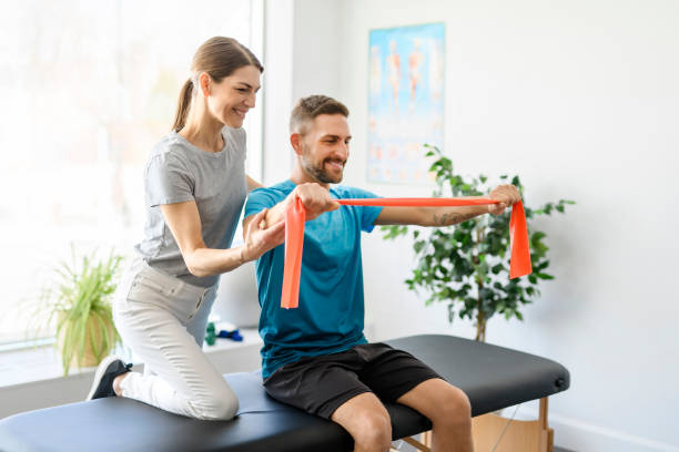 istock Modern rehabilitation physiotherapy woman worker with man client using red elastic 1397054285