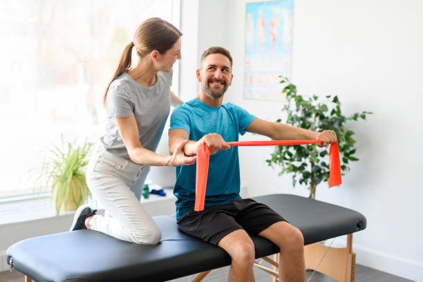 istock Modern rehabilitation physiotherapy woman worker with man client using red elastic 1397054288