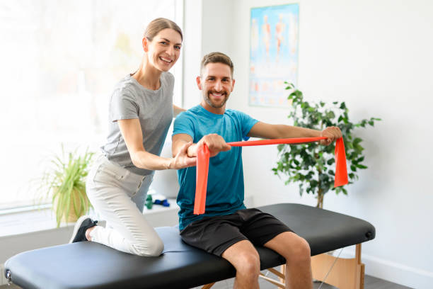 istock Modern rehabilitation physiotherapy woman worker with man client using red elastic 1397054291
