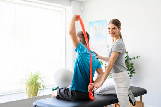 istock Modern rehabilitation physiotherapy woman worker with man client using red elastic 1397054305