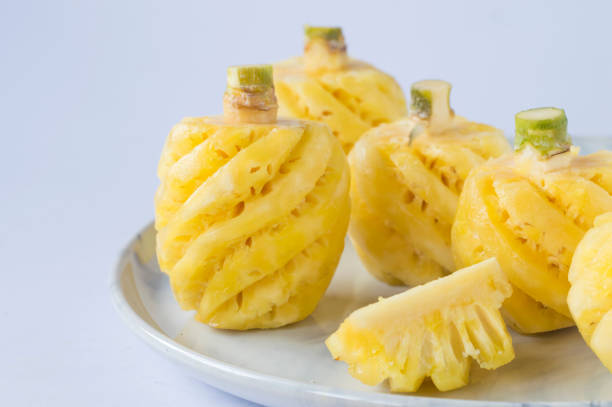 peeled yellow flesh pineapple in a white plate on a white background