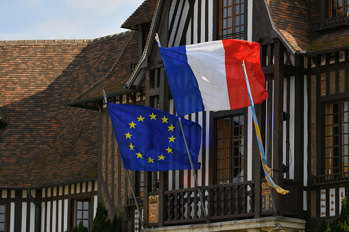 DEAUVILLE, FRANCE - APRIL 21, 2022 : The blue european flag and flag of France hanging on the city hall.