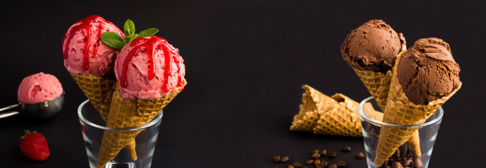 Banner. Close-up on chocolate and strawberry  ice cream in the waffle cone on the black background. Copy space.