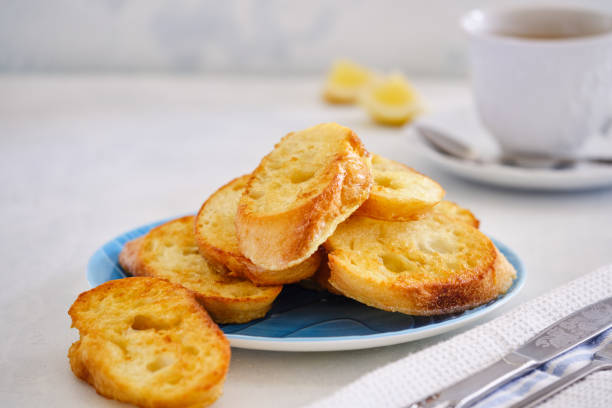 crushing slices of baguette on a plate with a cup of tea. - kruton stok fotoğraflar ve resimler