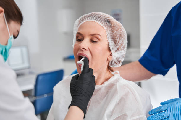Attentive nurse spraying anaesthesia at the female patient mouth before the endoscopy stock photo