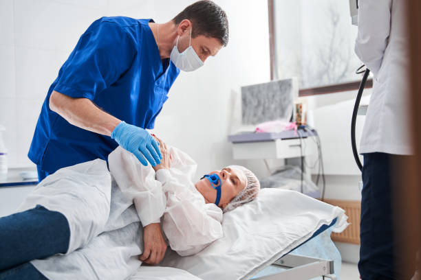 Doctor talking with his patient woman laying at the hospital bed before the colonoscopy stock photo