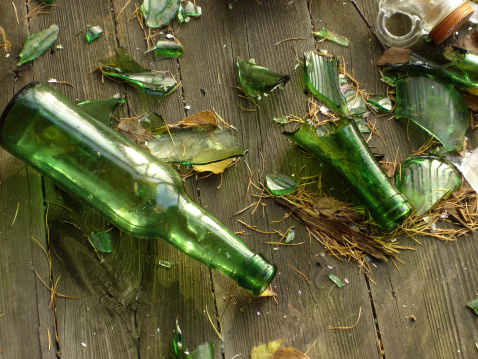 Grungy green glass bottles on wooden floor boards. Levels adjusted for increased contrast.