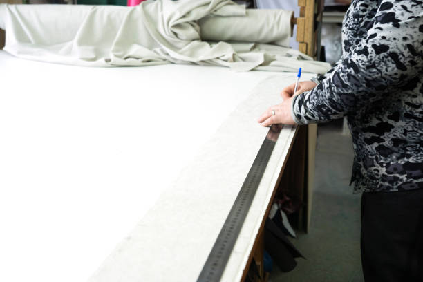 istock The seamstress or tailor measures the fabric on the sewing table using a rulerand a pen. Sewing workshop. Furniture manufactory. 1397059655