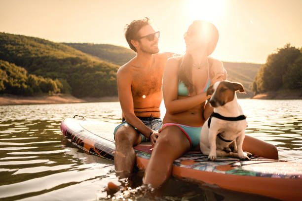 istock Couple paddle boarding at sunset with dog next to them 1397060852