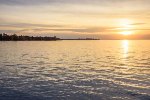 Photo of Majestic sunset over a lake in autumn. Wind turbines on an island are visible in distance.