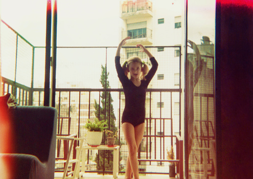 Analog image from the seventies featuring a girl dancing ballet on the balcony at home.