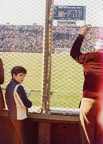 Vintage image of a boy at a soccer game in the stadium. Grainy analog image from the seventies.
