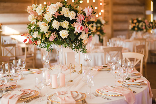 Puesta de mesa en la recepción de la boda. Composiciones florales con hermosas flores y vegetación, velas, colocación y platos en una mesa decorada. photo