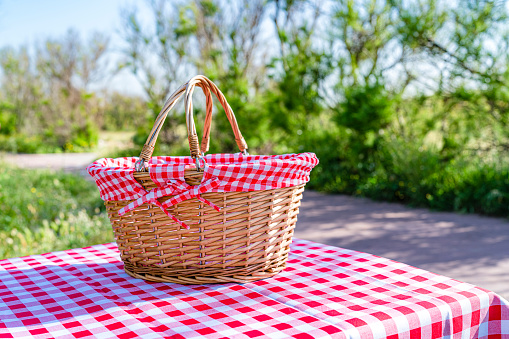 Empty picnic basket on a natural parkland wooden table. High resolution 42Mp outdoors digital capture taken with SONY A7rII and Zeiss Batis 40mm F2.0 CF lens