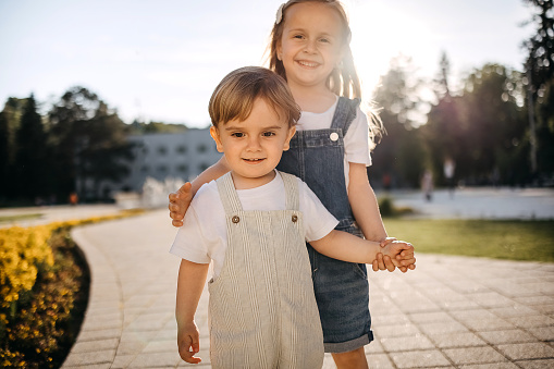 Shot of an adorable little girl and her smaller brother standing outside