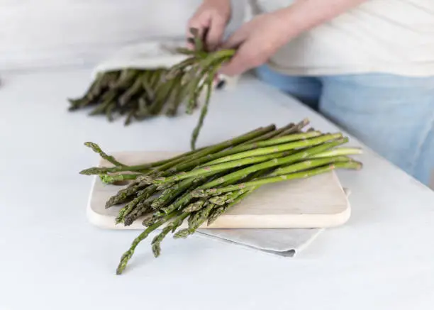 A woman holds a large bunch of fresh green asparagus in her hands. Healthy food and diet. Support for local business.