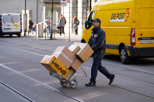Shopping mile Bahnhofstrasse with delivering van of Swiss Post company. Photo taken March 21st, 2022, Zurich, Switzerland.