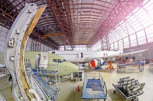 View from the aircraft with the door open to the aircraft hangar and the aircraft being there for technical maintenance