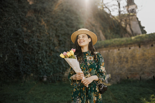 Portrait of young woman holding bouquet of tulips