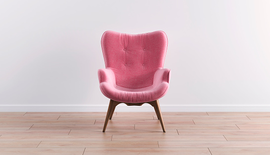 Fashionable modern pink armchair with wooden legs against a white wall in the interior. Furniture, interior object, modern designer armchair. Stylish minimalist interior.