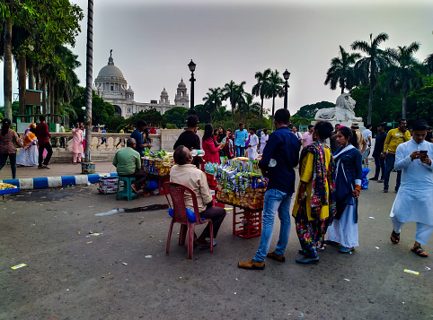 Kolkata wb India - May 03, 2022 : Taken this picture in front of Kolkata's Victoria Memorial of the street vendors selling to the tourist. It was cloudy evening but still tourists  crowded and visited the place.