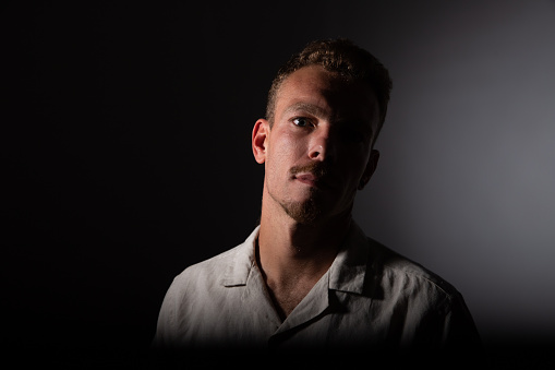 Portrait of a man in the dark, half of the face in shadow, pensive and gloomy mood