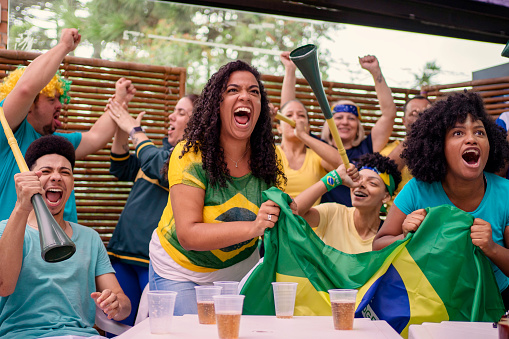 Brazilian friends watching soccer game and cheering together