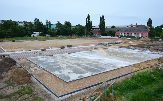 construction of a new stadium near the city school. earthworks and foundation pouring for playgrounds are being carried out