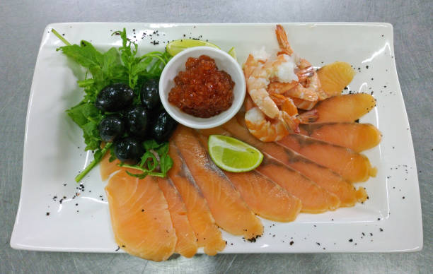 Seafood platter with salmon slice, red caviar and shrimps, olives and lime