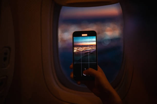 passeggero che scatta foto di paesaggi attraverso il finestrino dell'aereo con lo smartphone - wing airplane window sunset foto e immagini stock