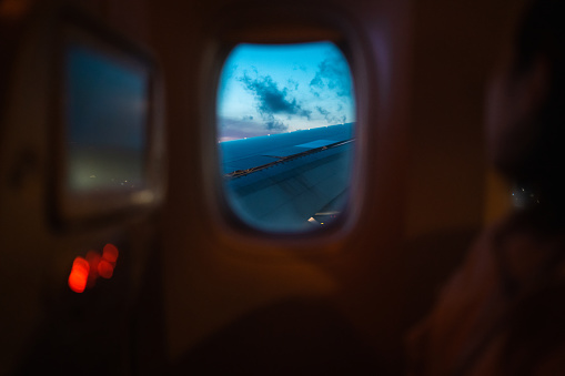 A passenger is looking at scenery through a window of an airplane.