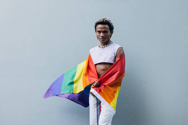 istock Man with a pride flag posing on grey background outdoors 1397090377