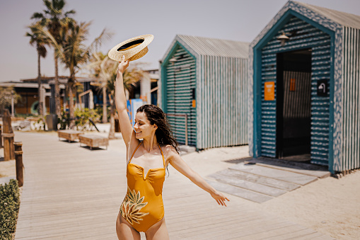 Young beautiful woman wearing one piece swimsuit with broad brim straw hat posing