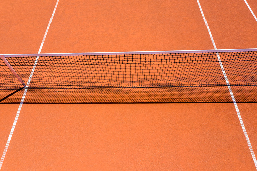 Close-up of tennis clay court, aerial view, net and centre service line, single sidelines.