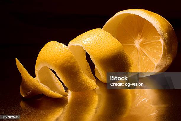 A Half Peeled Lemon With The Peel In A Twist On A Dark Back Stock Photo - Download Image Now
