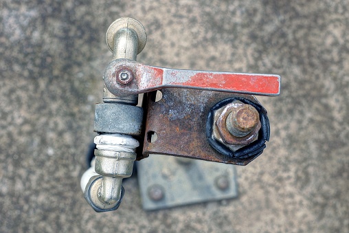 one gray water faucet with a red metal handle outdoors on a gray background